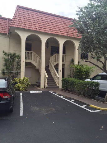 Front view of a two-story building with red roof tiles and arches.