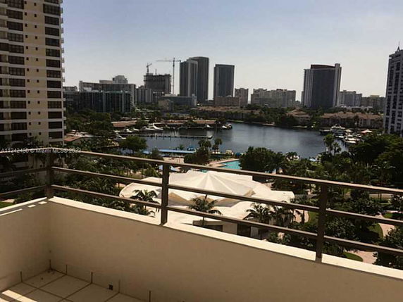 View from a balcony overlooking a cityscape with tall buildings, a lake, and greenery.