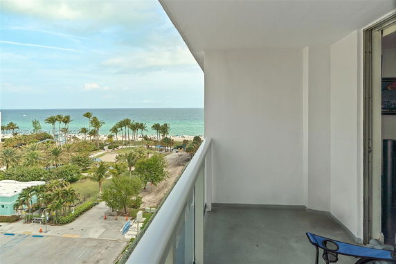 Balcony view overlooking the ocean and palm trees.