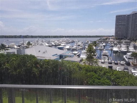 View of a marina with multiple boats docked and high-rise buildings in the background.