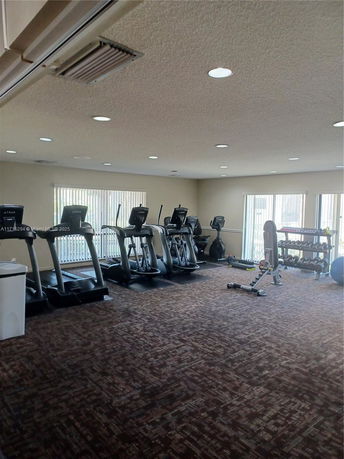 Indoor gym area with exercise equipment including treadmills and weights.