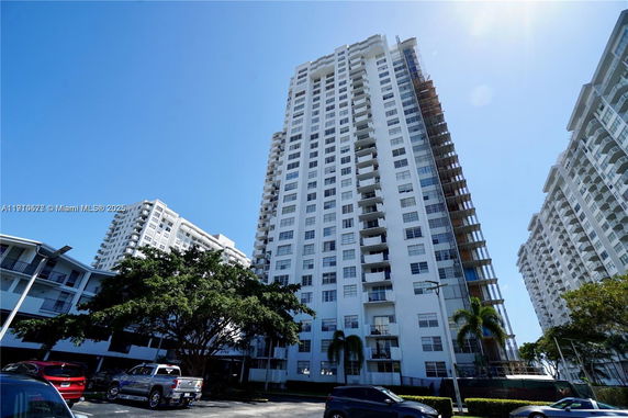 Front view of a tall residential building with multiple floors and balconies.