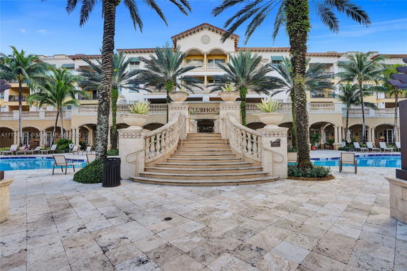 Outdoor view of a luxurious building with a swimming pool and grand staircase leading to a clubhouse entrance.