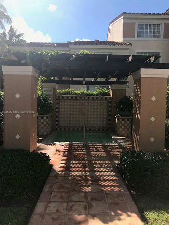 Outdoor view of a small tiled pool area with a pergola.