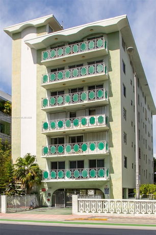 Front view of a multi-story building with decorative green balconies.