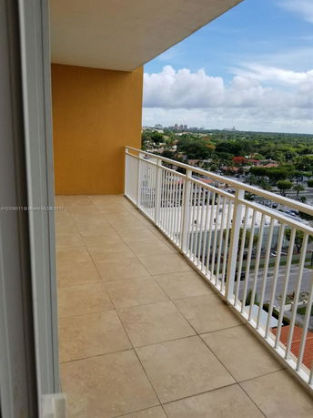 Balcony view showing surrounding area of residential and greenery.