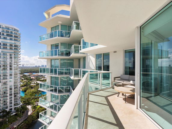 View from a balcony of a high-rise building showing nearby buildings and a pool area.