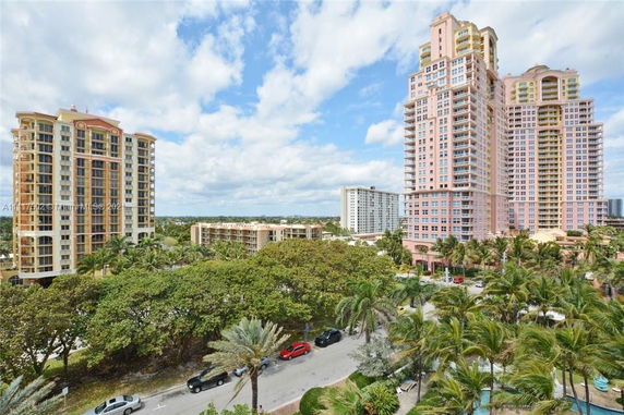 View of high-rise residential buildings with palm trees and a road in the foreground.