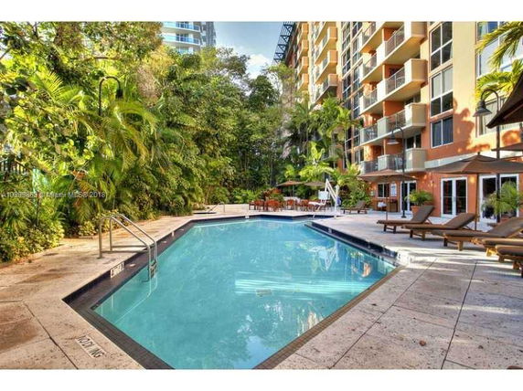 View of the outdoor pool area adjacent to a multi-story building with balconies.