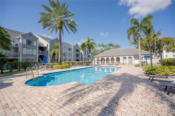 Outdoor swimming pool area with surrounding apartment buildings and palm trees.