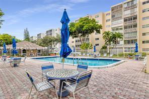 Outdoor swimming pool area with chairs and tables next to an apartment building.