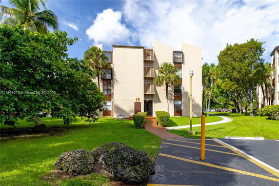 Front view of a mid-rise apartment building with trees and greenery.