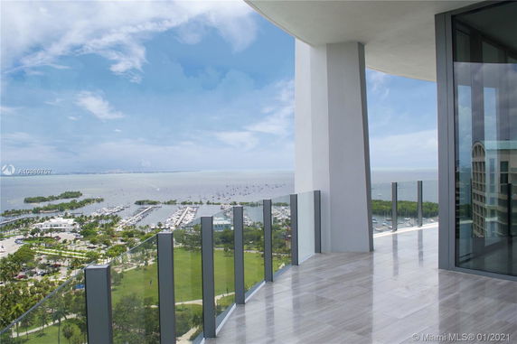 View from a high-rise balcony overlooking a marina and ocean.