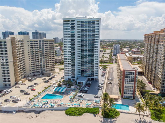 Aerial view of a high-rise building with a pool area and beach access.