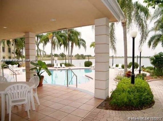 Outdoor swimming pool area with surrounding palm trees and patio furniture.