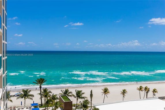 Panoramic view of the ocean and beach with palm trees from a building.