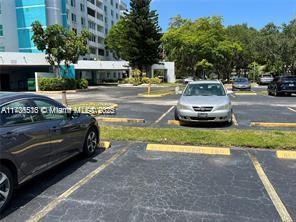 Outdoor parking area with multiple cars parked near a multi-story building.