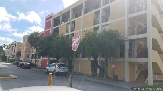 Front view of a multi-story apartment building with external staircases and balconies.