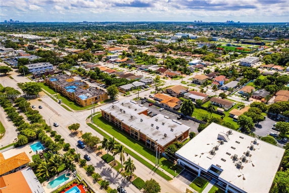 Aerial view of a suburban area with residential and commercial buildings, roads, and greenery.