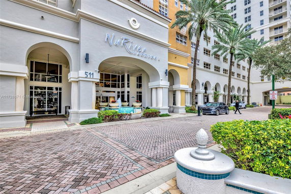 Front view of a multi-story residential building with arched entrances and palm trees.