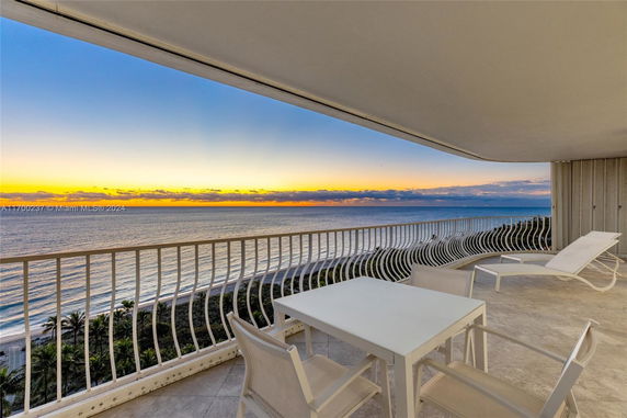 Panoramic view of the ocean seen from a balcony with patio furniture.
