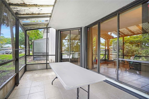 Outdoor area with a tiled floor, folding table, and glass sliding doors.
