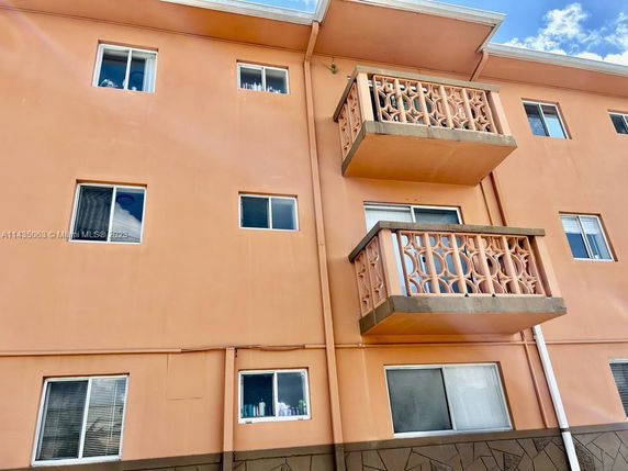 Front view of a multi-story building with balconies and rectangular windows.