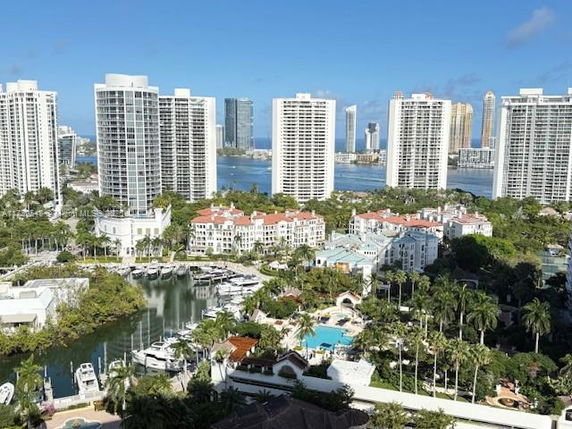Panoramic view of tall buildings near a waterfront with boats and greenery.
