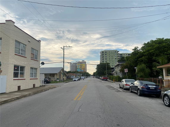 Street view with apartment buildings and parked cars.