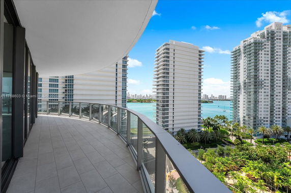 Panoramic view of high-rise buildings and a water body from a curved balcony.