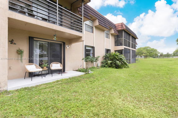 Rear view of a multi-story building with balconies and outdoor seating area.