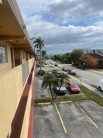 View of a building with adjacent outdoor parking spaces and cars.