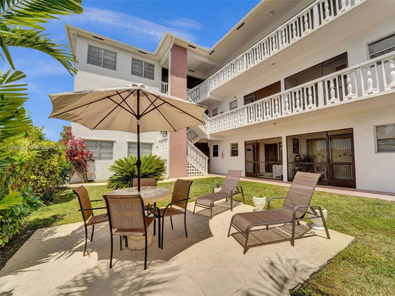 Front view of a multi-story building with balconies and outdoor seating area.