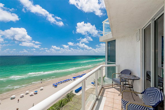 Coastal view from a balcony overlooking the ocean and beach with deck chairs.