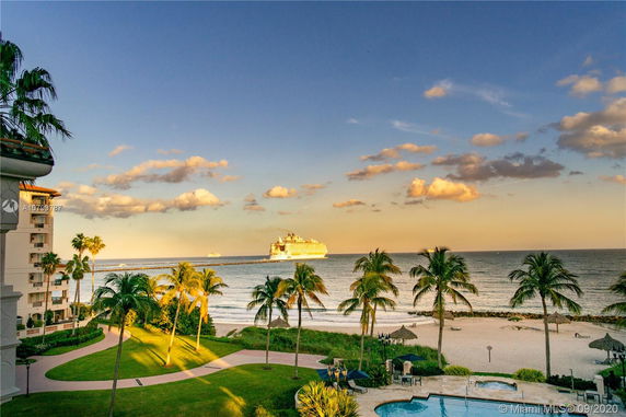 Panoramic view of the ocean with a cruise ship, beach, and palm trees.