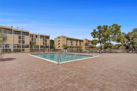 Outdoor swimming pool area with surrounding multi-story buildings.