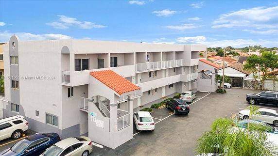 Front view of a multi-story residential building with external staircases and parking area.