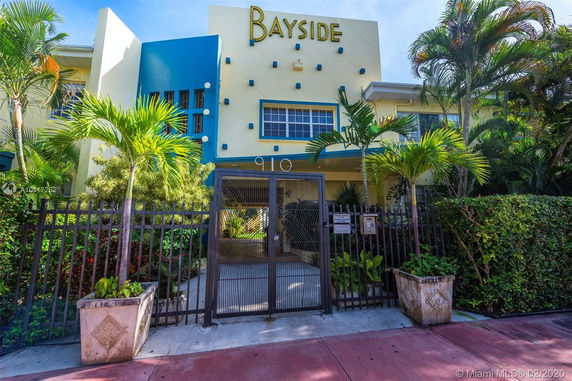 Front view of a building with a gated entrance and tropical landscaping.