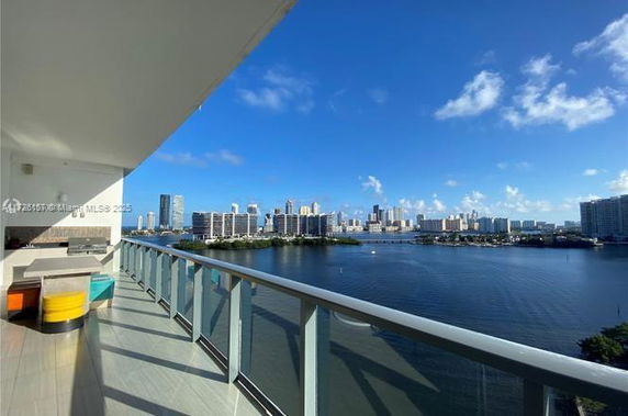 Panoramic view from a balcony overlooking a body of water and city skyline in the background.