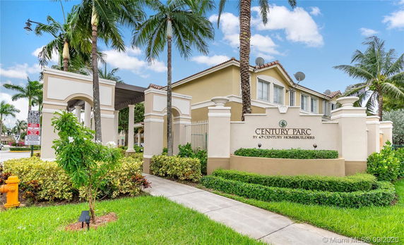 Front view of a residential complex with entry signage and palm trees.