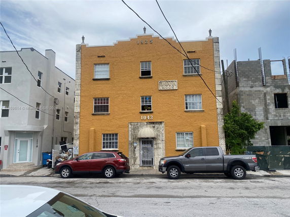 Front view of a three-story building with an orange facade and multiple windows.