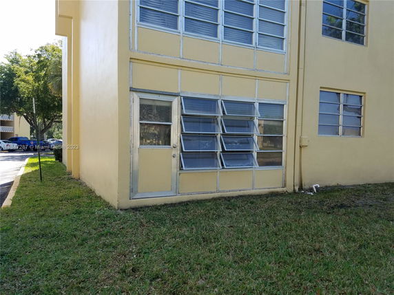 Front view of a yellow-painted building with large windows.