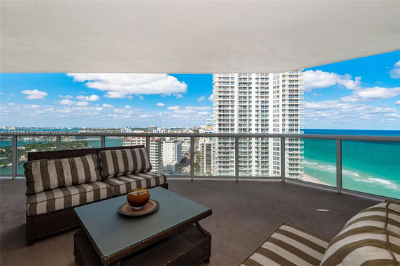 Panoramic view from a balcony overlooking high-rise buildings and the ocean.