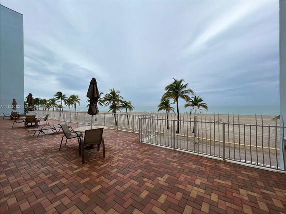 Outdoor area with chairs and umbrellas overlooking a beach and ocean.