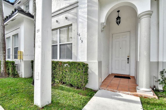 Front entrance of a house with an arched doorway and white walls.