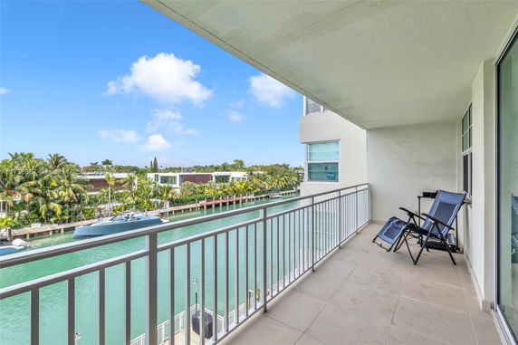 Balcony view overlooking a canal and surrounding houses with palm trees.