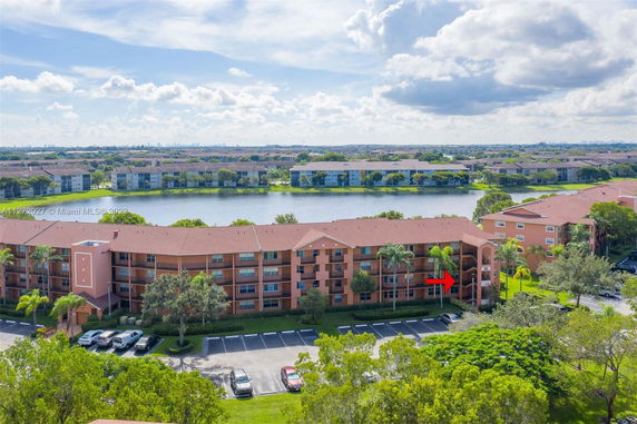 Aerial view of a multi-story apartment complex with surrounding landscape and water body.