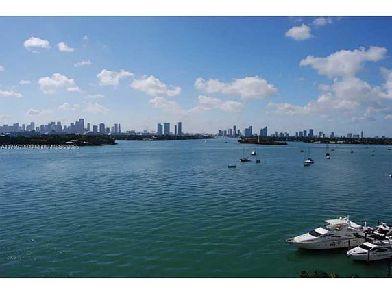 Waterfront view with yachts and a city skyline in the distance.