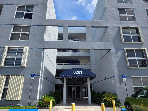 Front view of a multi-story building with a blue awning at the entrance marked 8201.