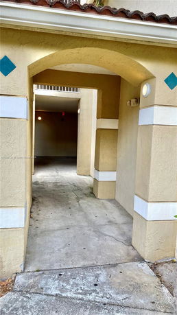 Front entrance of a building with an arched gateway and stucco walls.